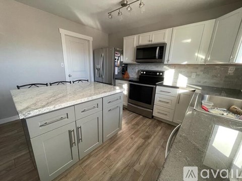 A kitchen with white cabinets and a granite countertop.