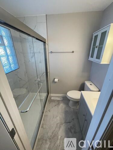 A bathroom with a glass shower door and a toilet.