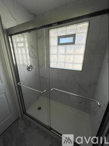 A bathroom with a glass shower stall and a marble wall.