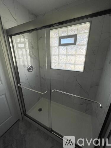 A bathroom with a glass shower stall and a marble wall.