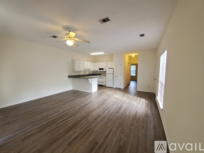 A spacious room with wooden flooring and a ceiling fan.