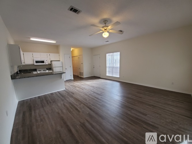 A spacious room with wood flooring and a ceiling fan.