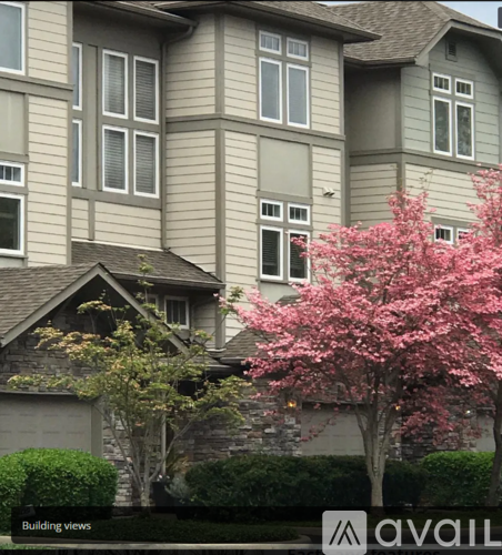 A tree with pink flowers in front of a grey building.