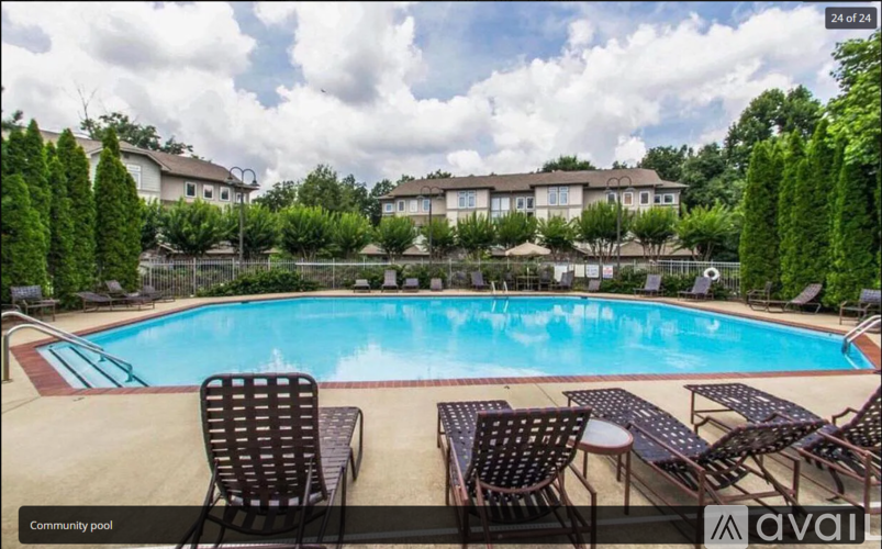 A community pool with chairs around it and houses in the background.