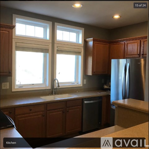 A kitchen with wooden cabinets and a stainless steel refrigerator.