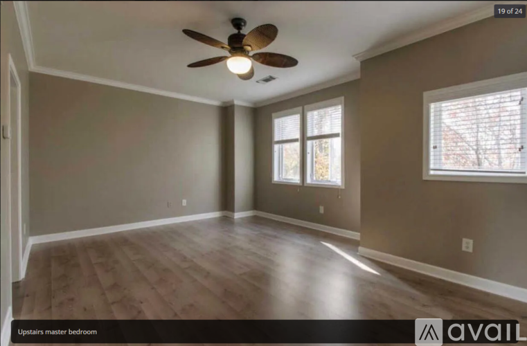A spacious room with a ceiling fan and two windows.
