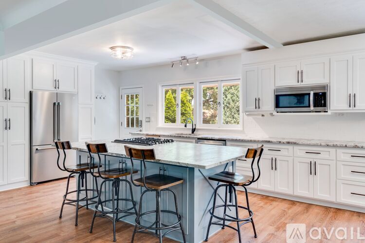A kitchen with white cabinets and a large island with bar stools.