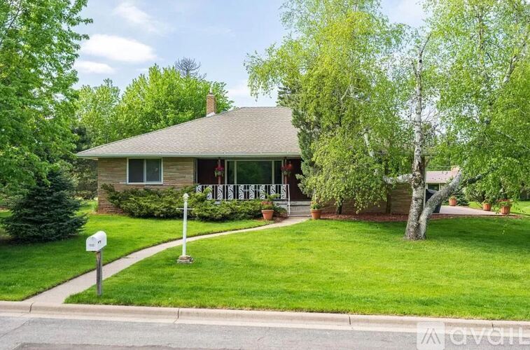 A house with a green lawn and trees in the background.
