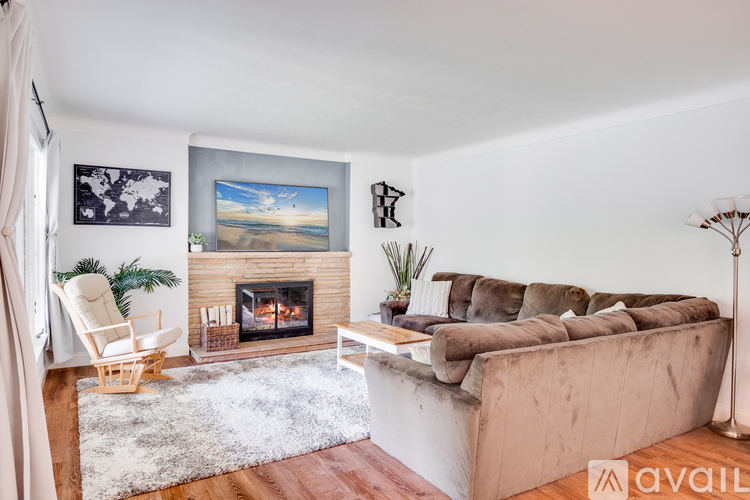A living room with a fireplace and a painting of a beach scene on the wall.