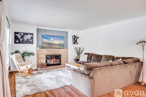 A living room with a fireplace and a painting of a beach scene on the wall.