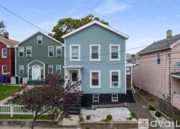 A blue house with a white door and windows is in front of other houses.