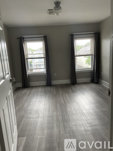 A room with two windows and a wooden floor.