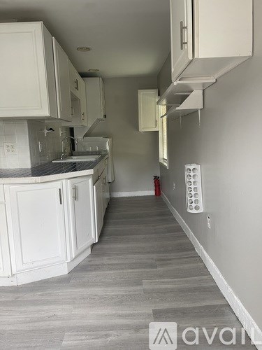 A kitchen with white cabinets and a grey floor.