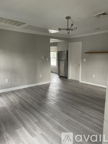 A spacious room with a wooden floor and a ceiling fan.