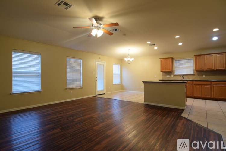 A spacious room with wooden floors and a ceiling fan.