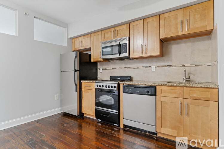 A kitchen with wooden cabinets and a black refrigerator.
