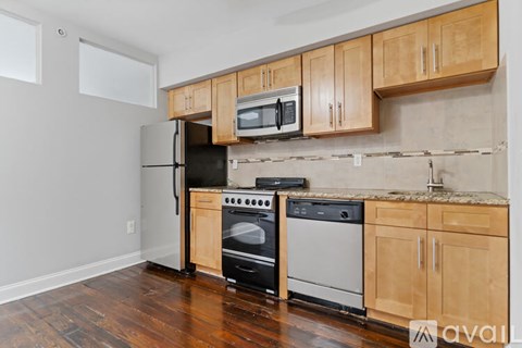 A kitchen with wooden cabinets and a black refrigerator.