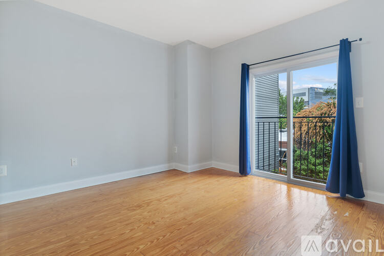 A room with wooden floors and a sliding glass door leading to a balcony.