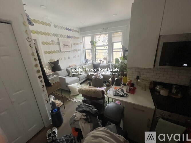 A cluttered living room with a couch, a fireplace, and a TV.