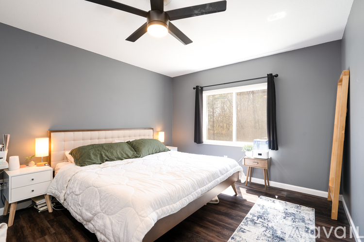 A bedroom with a white bed and a ceiling fan.