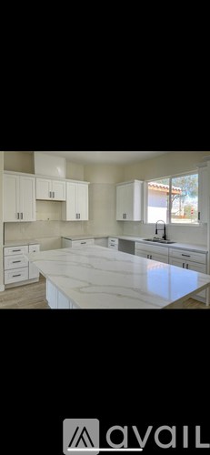 A kitchen with white cabinets and a marble countertop.