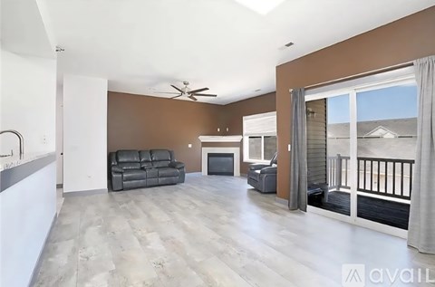 A spacious living room with a black leather sofa and a television.