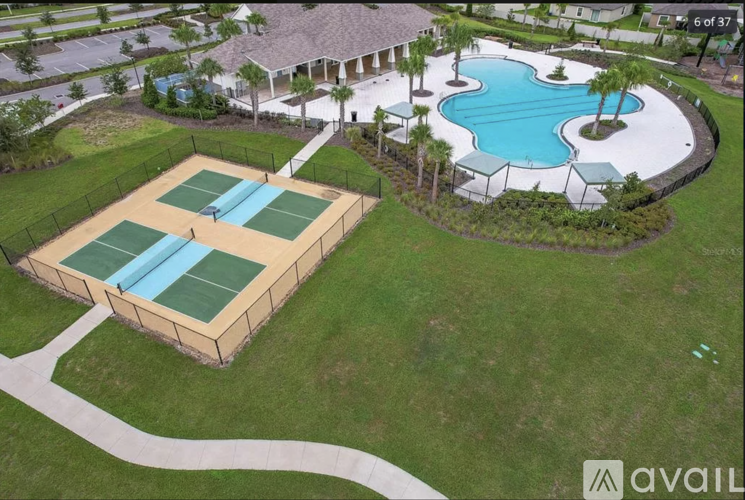 A tennis court and a swimming pool are surrounded by a fence.