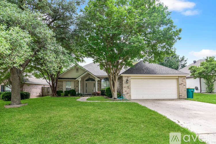 A house with a driveway and a tree in front.