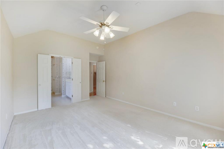 A spacious room with a ceiling fan and white walls.