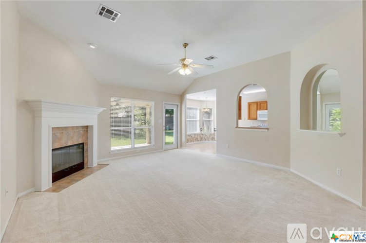 A spacious living room with a fireplace and a ceiling fan.