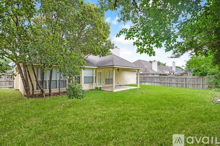 A house with a well-maintained lawn and trees in front.