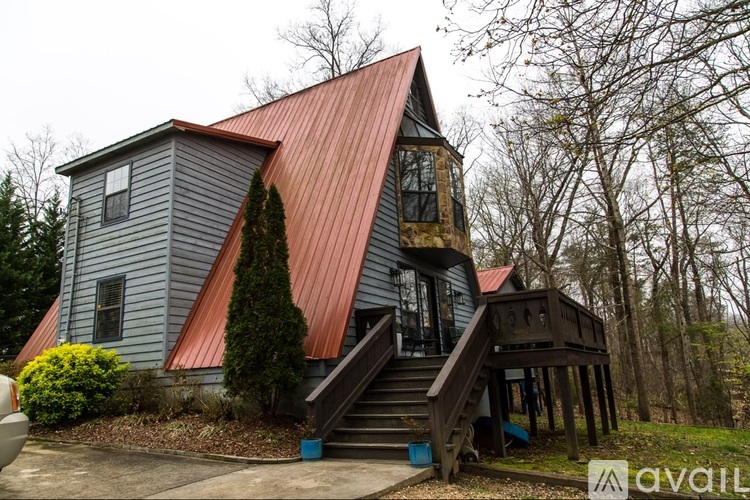 A house with a red roof and a staircase leading to a deck.