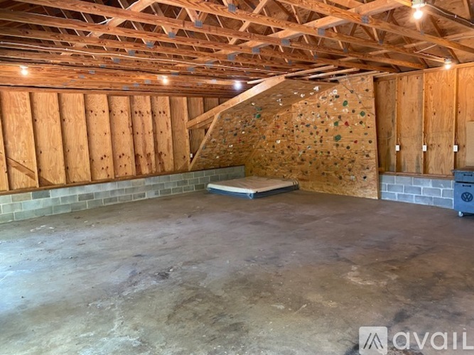 A sparsely furnished room with a climbing wall and wooden ceiling.