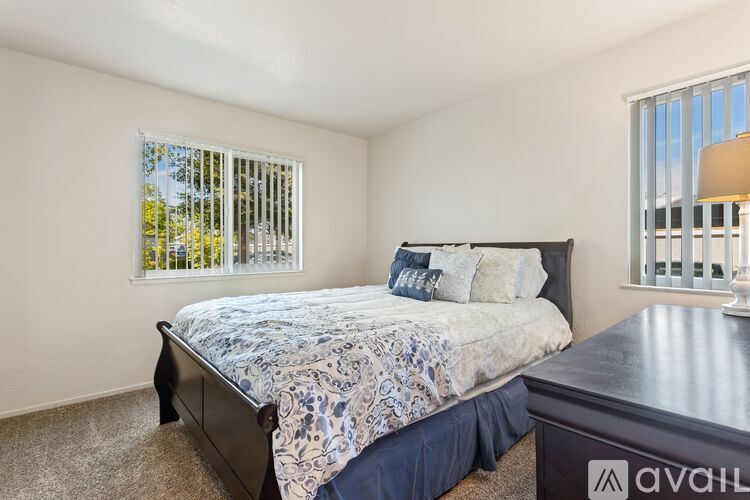 A bedroom with a bed, nightstand, and window with blinds.