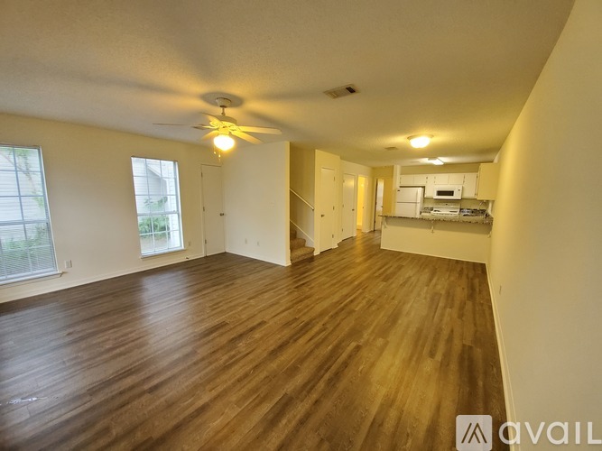 A spacious room with wooden flooring and a ceiling fan.