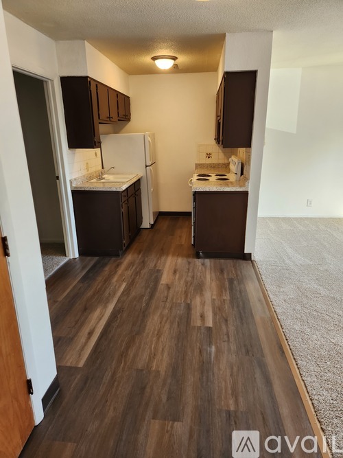 A kitchen with wooden floors and white appliances.