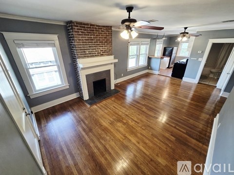 A room with a brick fireplace and wood flooring.