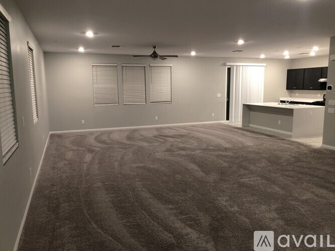 A spacious room with a carpeted floor and a ceiling fan.