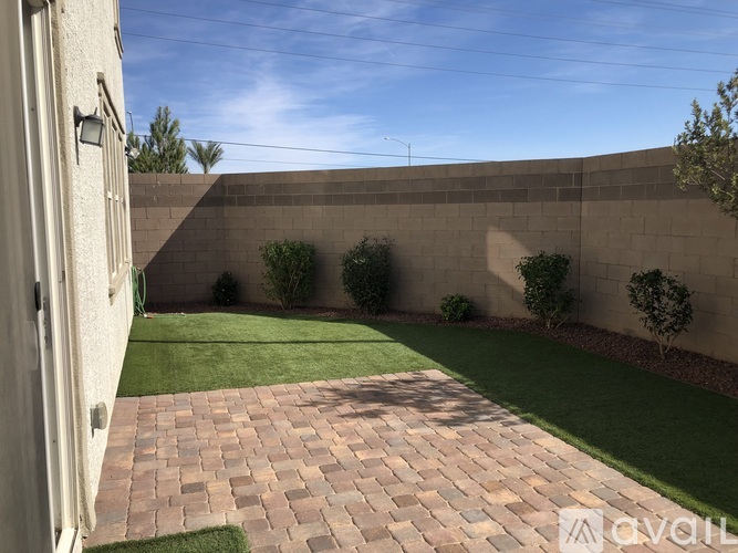 A backyard with a brick walkway and a wall.