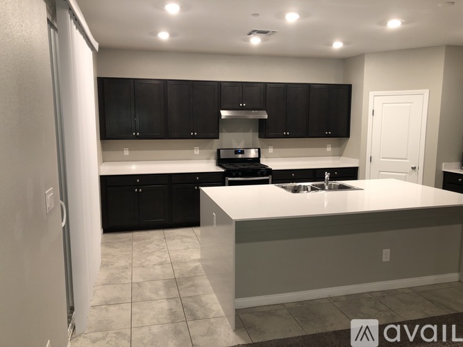 A kitchen with black cabinets and a white island.