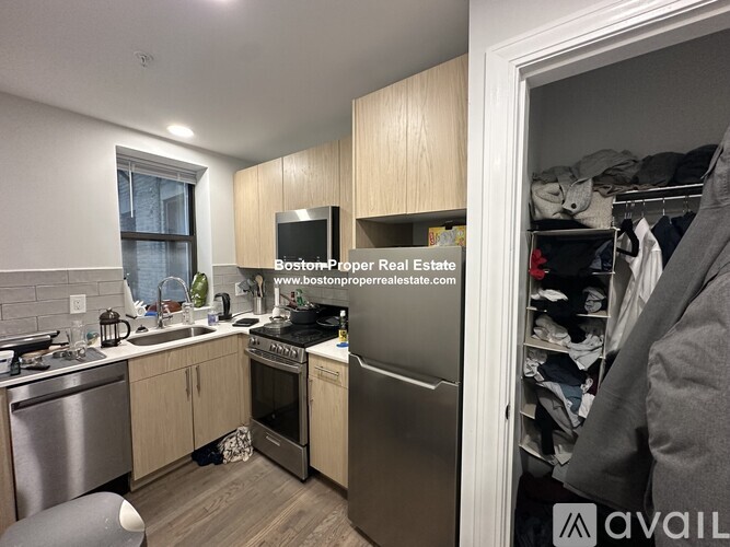 A kitchen with wooden cabinets and a stainless steel refrigerator.