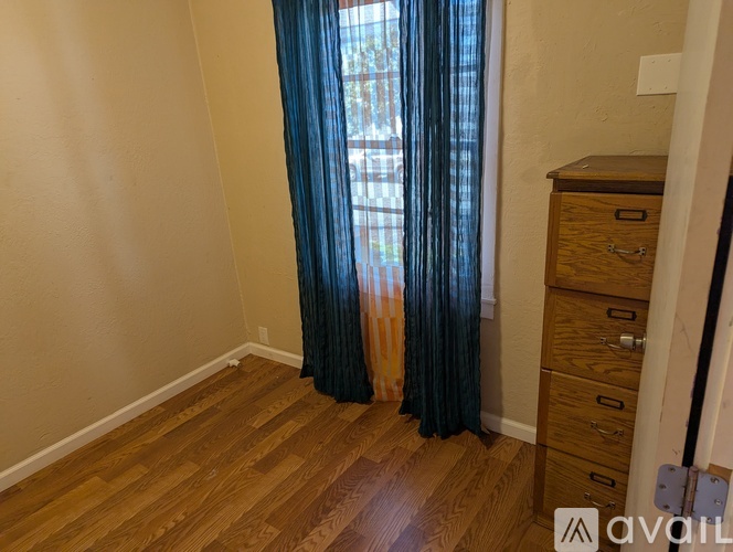 A room with wooden floors and a window with blue curtains.