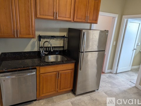 A kitchen with wooden cabinets and a stainless steel refrigerator.