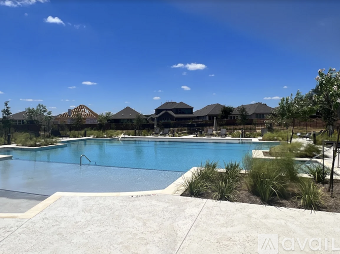 A large swimming pool surrounded by a concrete patio and greenery.