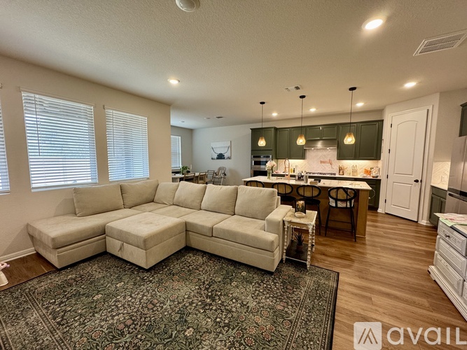A living room with a large sectional sofa and a rug.