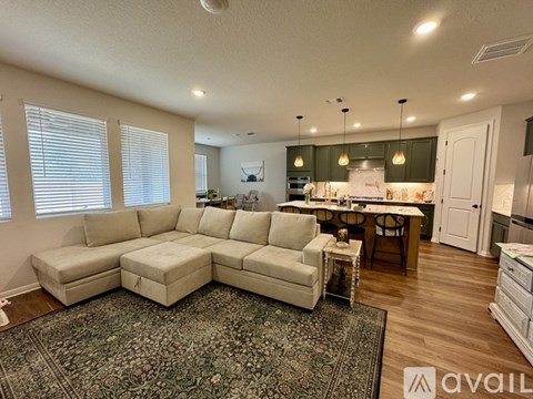 A living room with a large sectional sofa and a rug.