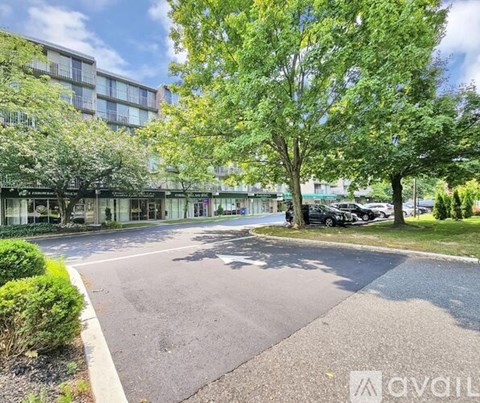 A parking lot in front of a building with a tree and bushes.