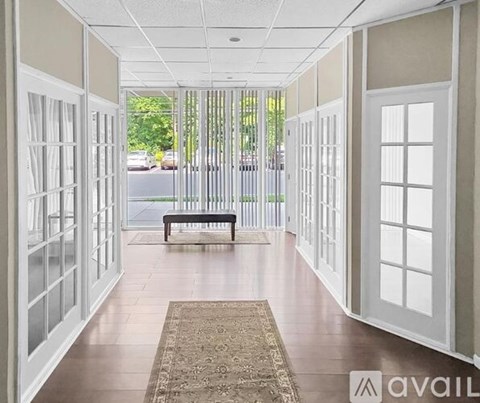 A hallway with white doors and a bench in the middle.