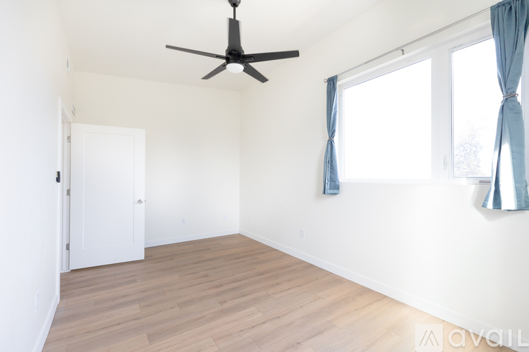 A room with a ceiling fan and a window with curtains.