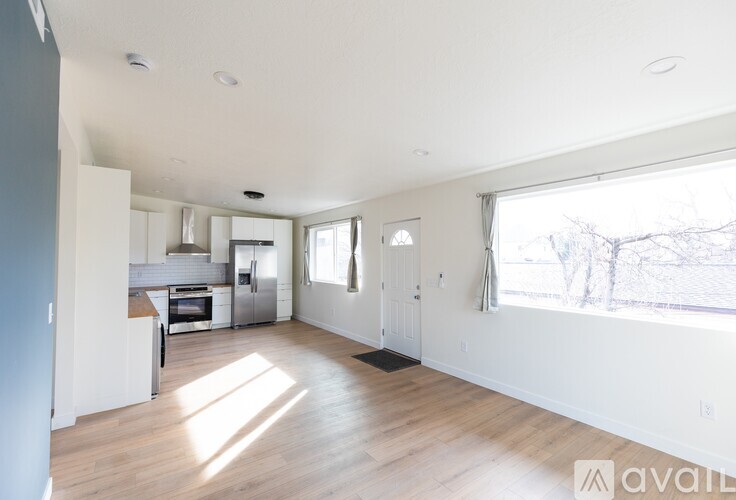 A spacious, empty living room with a kitchen in the background.